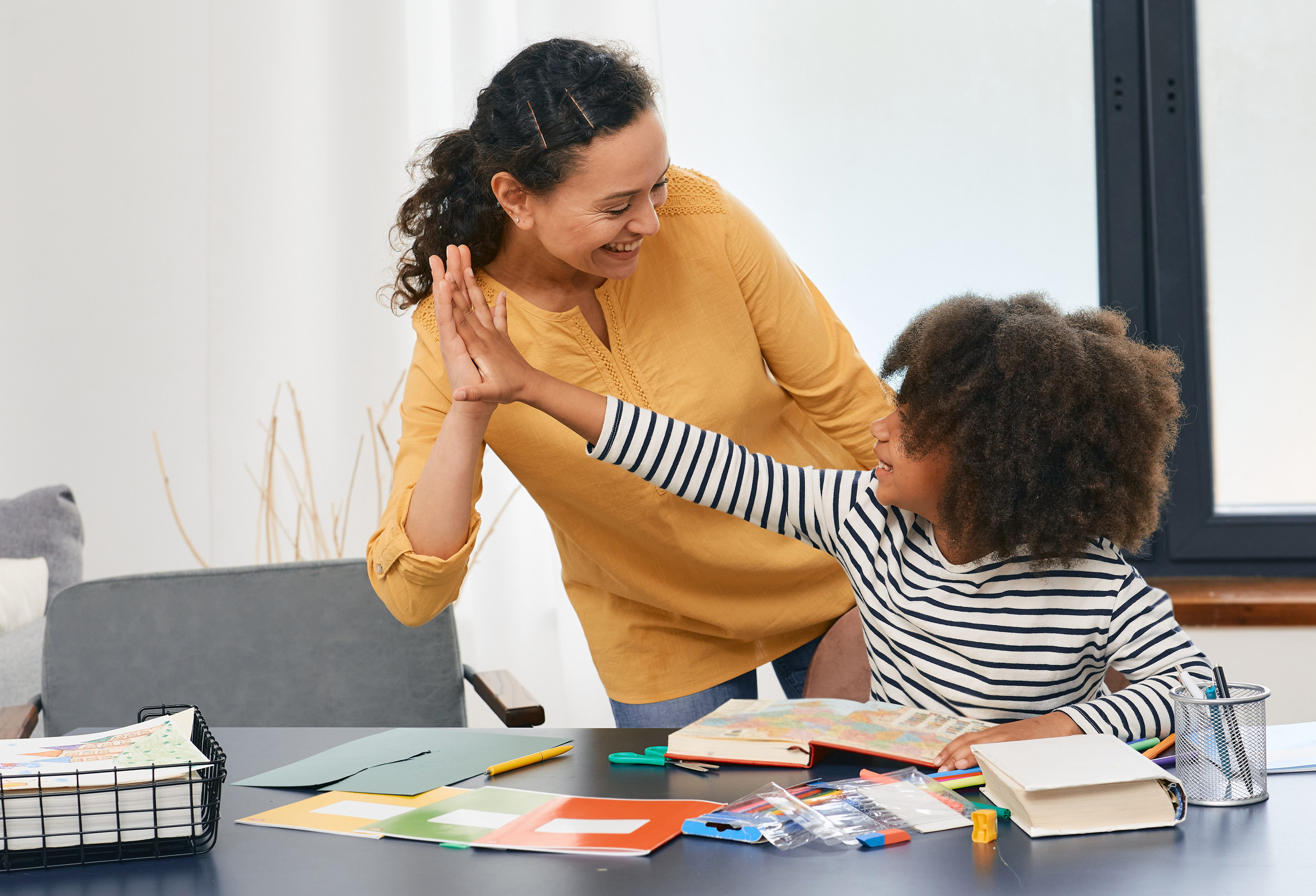 Child and teacher hi-fiving together on school work