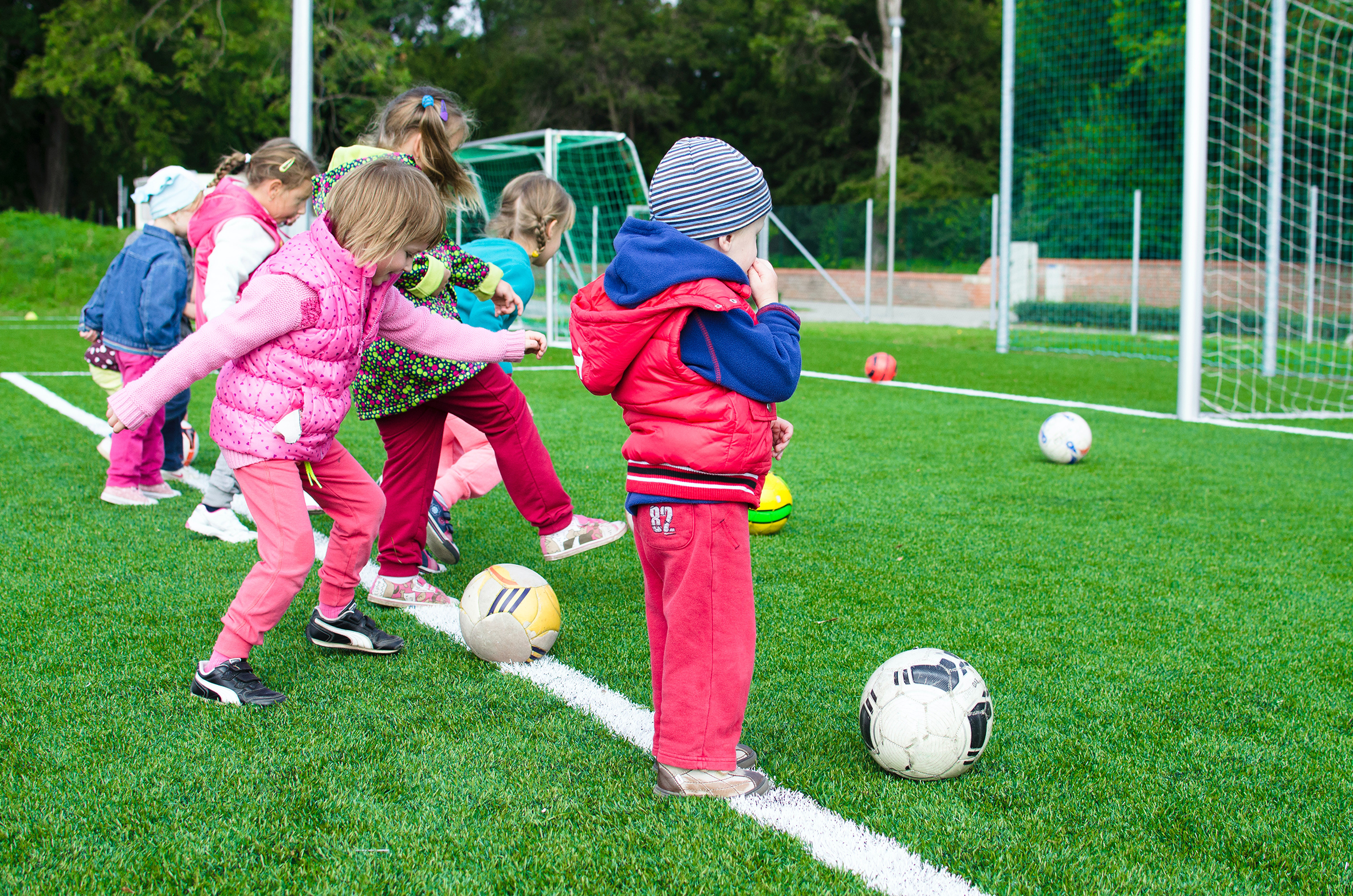 young children playing football on a playing field