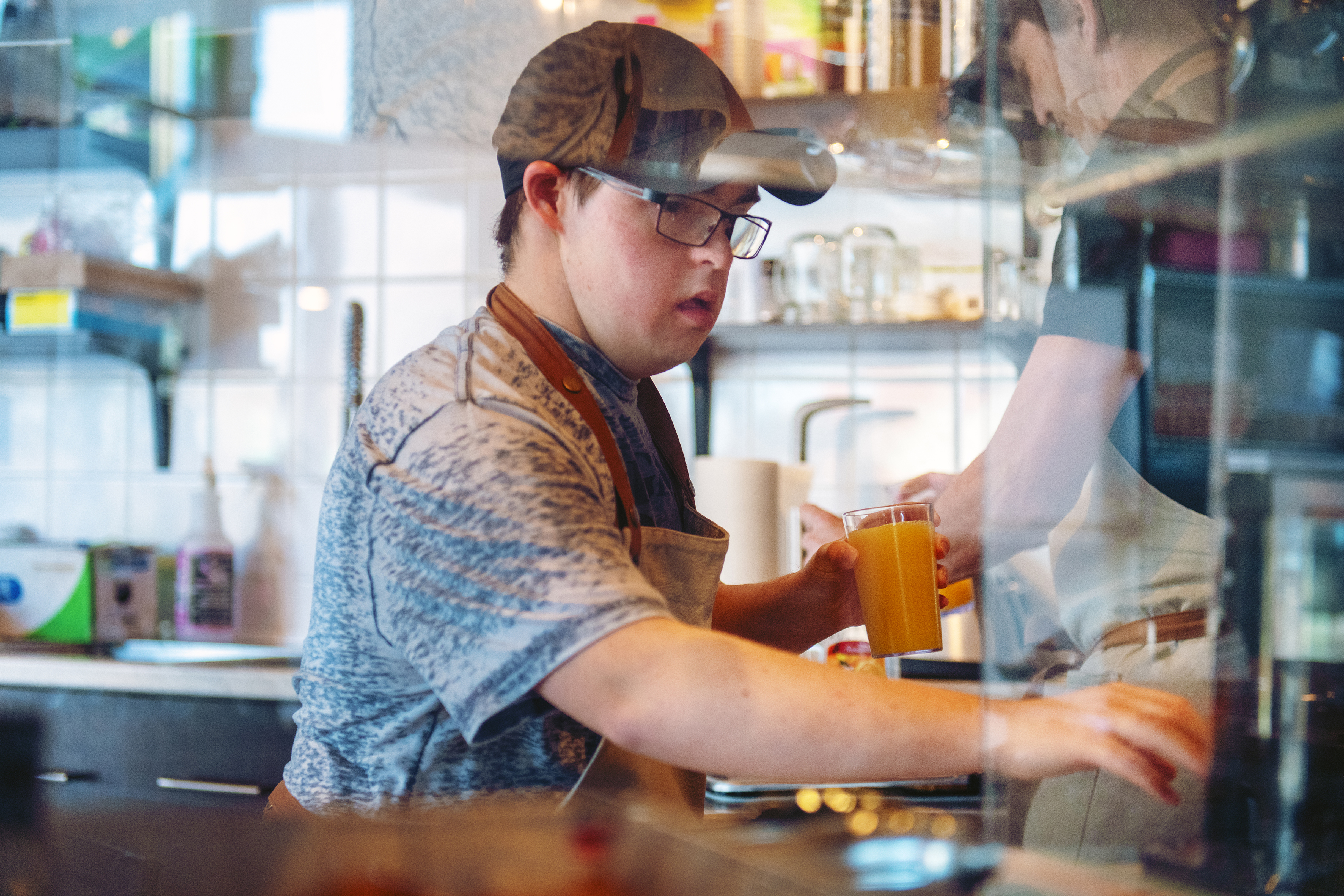 Young teenager working in a coffee shop serving juice