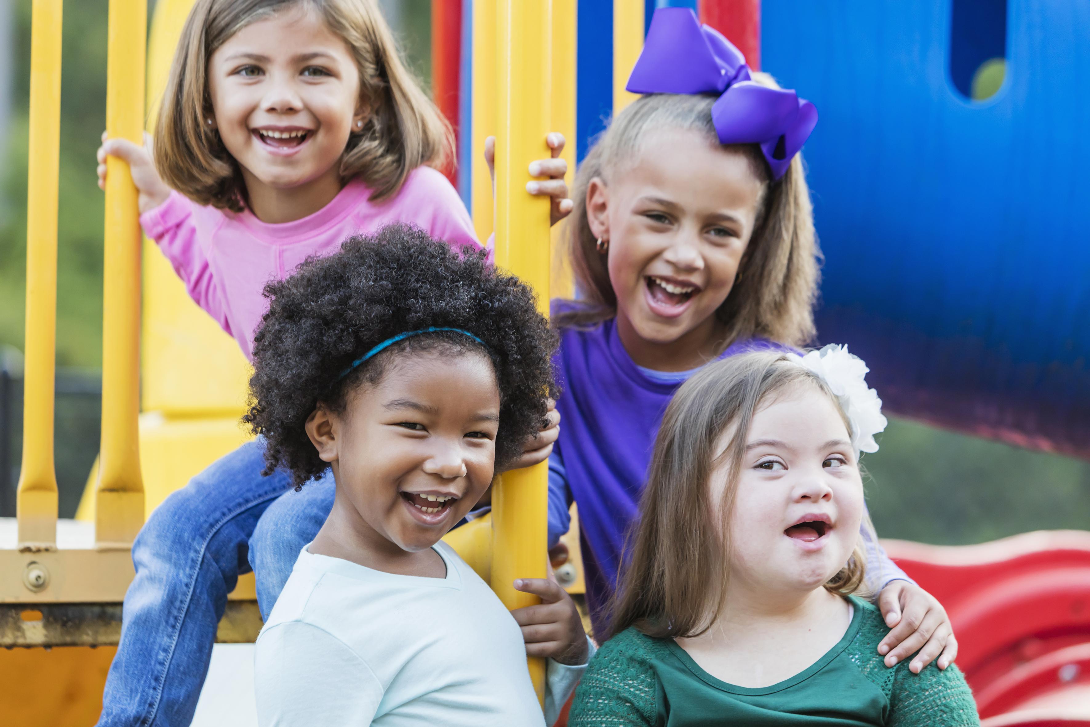 A group of four girls, 5 to 7 years old, playing outdoors on playground equipment